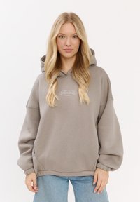 Przesadny, duszny sweatshirt w jasnoszarym kolorze z teksturowanym wykończeniem. Posiada małe, haftowane logo z przodu oraz ściągacze przy mankietach.