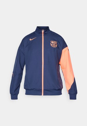 Ciemnoniebieska kurtka Nike FC Barcelona z koralowymi akcentami, z pełnym zamkiem, wysokim kołnierzem oraz logo na klatce piersiowej i rękawie.