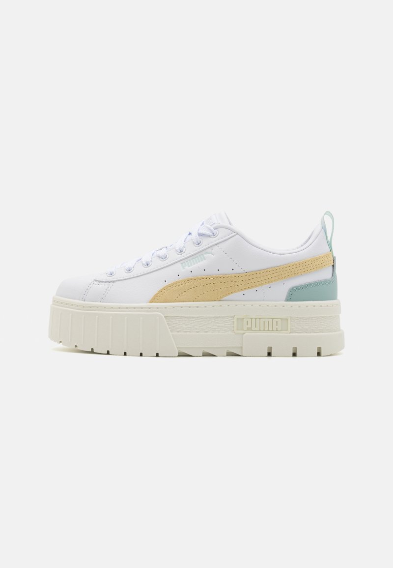 White sneaker with a chunky cream sole, beige accents, and a mint green heel tab. Features a textured surface and classic lace-up design.