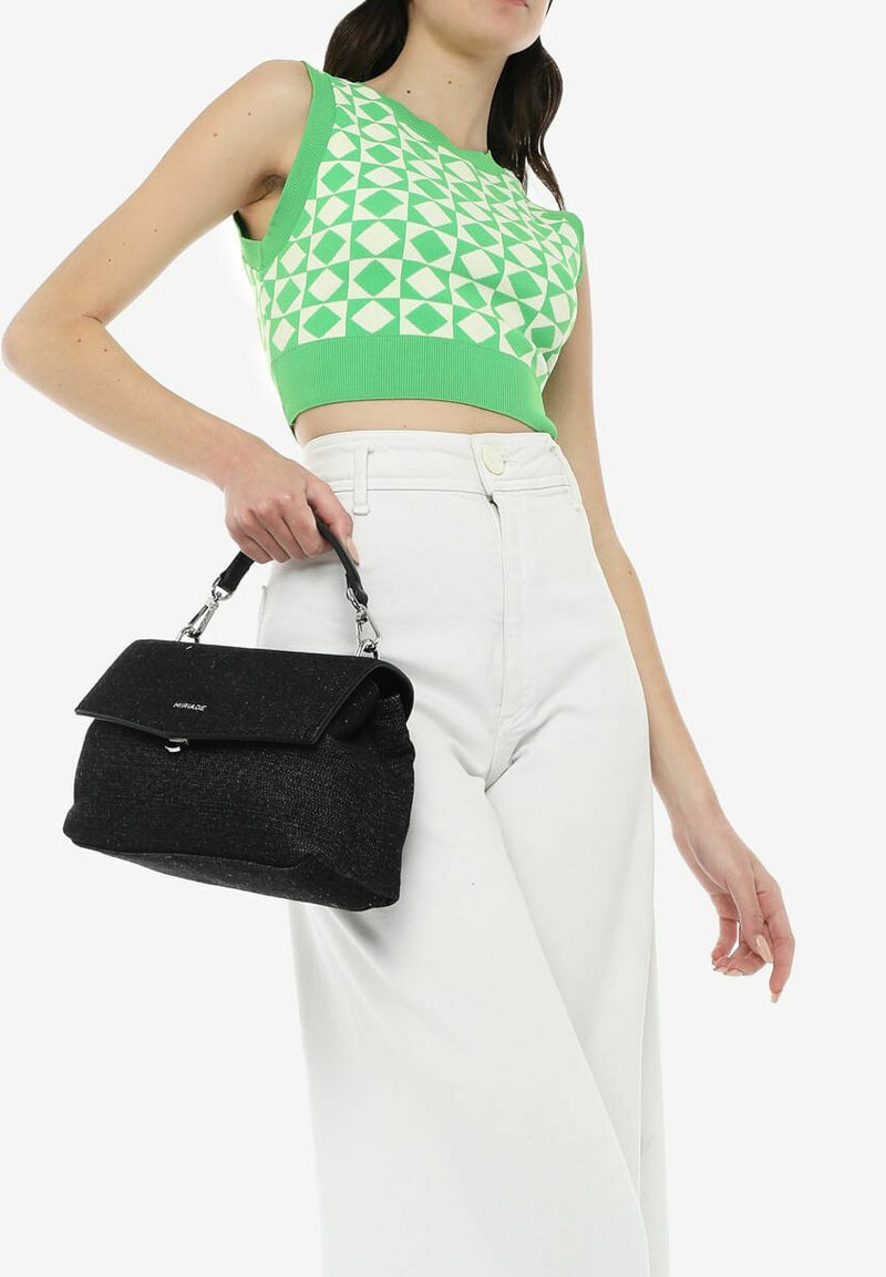 Borsa a tracolla nera in tessuto morbido, con chiusura a patta e accessori in argento. Indossata con un top corto a fantasia verde e pantaloni bianchi a vita alta.