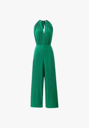 Combinaison verte sans manches à col halter avec un décolleté en V profond et un pantalon large, dotée d'un nœud au niveau du cou et d'un tissu texturé.