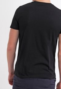 Svart bomullströja med rund hals och korta ärmar. Slät struktur med en figurnära silhuett. Inga synliga logotyper eller mönster.