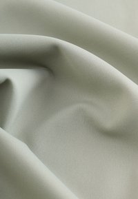 Világoszöld szövet, sima, szőtt textúrával, lágy redőzéssel és finom fényességgel. Látható minták vagy fémes részletek nélkül.