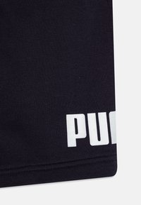 Țesătură din bumbac negru cu margini rotunjite, prezintă text mare alb "PUMA" pe partea dreaptă, textură fină, design minimalist.