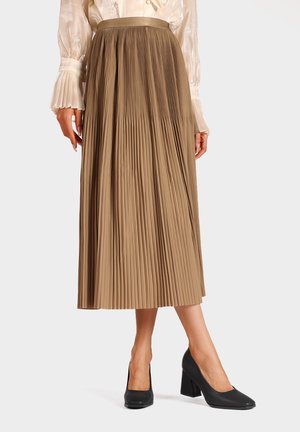 Gonna midi plissettata in tessuto marrone chiaro con una texture liscia e una vita alta, abbinata a scarpe con tacco nere.
