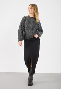 Melna adīta džemperis ar plašu kakla izgriezumu, apvienots ar melnu denima maksi svārku ar priekšējo šķelumu un akcentētiem melniem zābakiem līdz ceļgaliem.