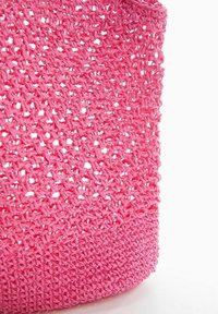 Sac fourre-tout tissé rose avec un design en tricot ouvert et une finition texturée. Le fond comporte une bande rose solide pour plus de structure.