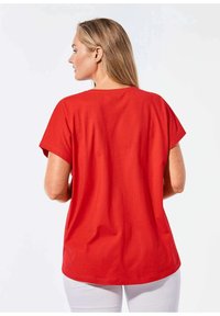 Rotes T-Shirt mit kurzen Ärmeln, entspanntem Schnitt und Rundhalsausschnitt. Weiches Baumwollmaterial, glatte Textur und ein schlichtes Design.