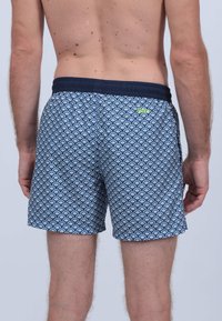 Shorts de bain avec un motif en coquillage bleu et blanc, taille élastique et poches latérales. Fabriqués en tissu léger.