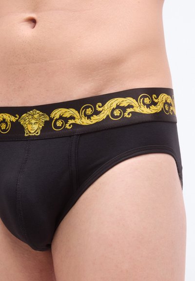 Caleçons pour hommes noirs avec une ceinture dorée ornementale présentant des motifs de feuilles détaillés et un design de médaillon central.