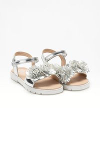 Sandali metallici argento con due cinturini, dotati di tre decorazioni floreali. Suola leggera bianca con soletta beige liscia.