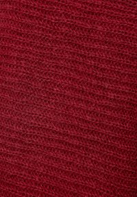 Dziane tkanina w głębokim czerwonym kolorze z teksturowanym wzorem. Materiał wydaje się miękki i ciepły, z lekko nierównym splotem.