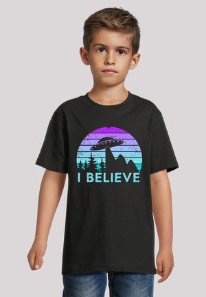 Black t-shirt featuring a colorful graphic with mountains, trees, and a UFO, with the phrase "I BELIEVE" prominently displayed.
