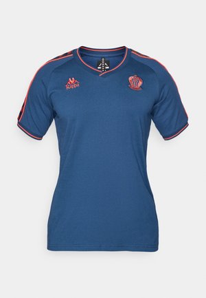 Blaues Sportshirt mit roten Akzenten, verfügt über einen V-Ausschnitt, kurze Ärmel und bestickte Logos auf der Brust und Schulter. Weiche Stoffstruktur.
