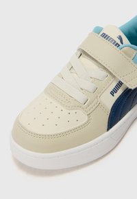 Beige és kék sneaker bőrből készült felsőrésszel, perforált orrrésszel, fehér talppal, valamint fűzővel és tépőzáras pánttal. Puma logó az oldalon.
