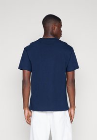 Camiseta de manga corta color navy vista desde la parte posterior. Fabricada en algodón, cuenta con un cuello redondo y un ajuste relajado con una textura suave.