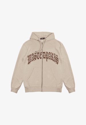 Sweat à capuche beige clair zippé avec poches avant et texte marron de style gothique "WASTEDPARIS" sur la poitrine.