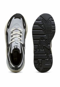 Šedé a černé sportovní boty s prodyšným svrškem, silnou podešví a texturovanou černou podrážkou s zakřivenými vzory. Šnúrky jsou bílé.