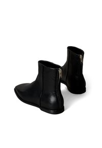 Stivaletti alla caviglia in pelle nera con punta affilata, chiusura laterale con cerniera e texture liscia. Presentano suole robuste e cuciture a contrasto.