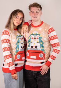 Strickweihnachtspullover in Beige und Rot, die einen Eisbären mit einem Weihnachtsbaum, bunte Akzente und Schneeflockenmuster an den Ärmeln zeigen.