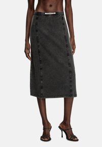 Svart denim midi-kjol med diagonala sömmar, en figursydd midja och rak silhuett. Bärs med remsandaler med hög klack.