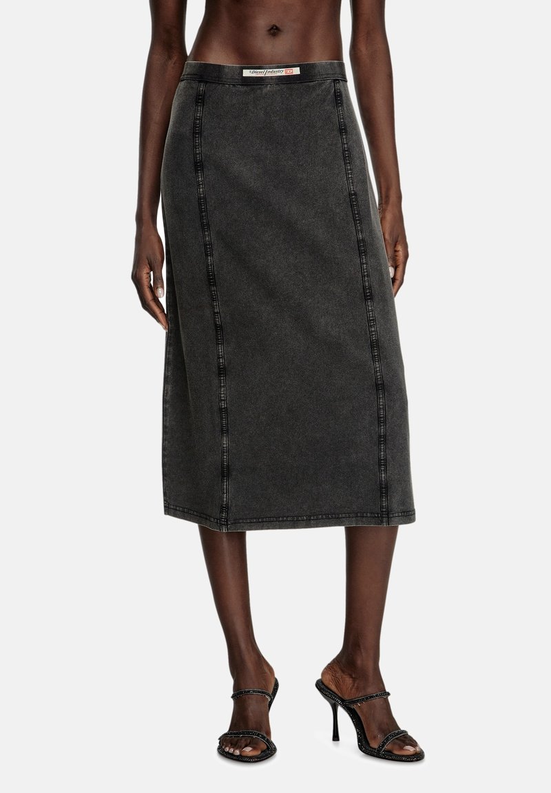 Svart denim midi-kjol med diagonala sömmar, en figursydd midja och rak silhuett. Bärs med remsandaler med hög klack.