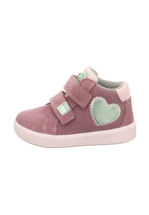 Sneaker in suede rosa con due cinturini in Velcro, interno grigio e dettaglio a forma di cuore verde sul lato. Suola piatta in gomma con grip testurizzato.
