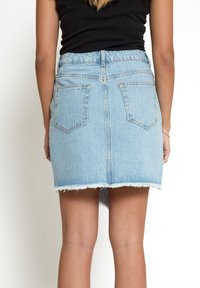 Gonna in denim azzurro chiaro con orlo sfrangiato, due tasche posteriori e chiusura con zip. Il design presenta una silhouette aderente con vita alta.