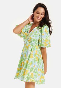 Short-sleeve, knee-length dress featuring a floral pattern in green, yellow, and blue. V-neckline and cinched waist with buttons.