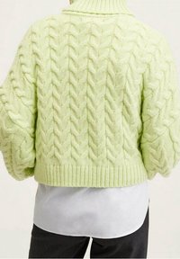 Pull en mailles torsadées cropped dans un vert clair, avec un col haut, des manches oversized et un ourlet côtelé. Texture douce avec un motif épais.