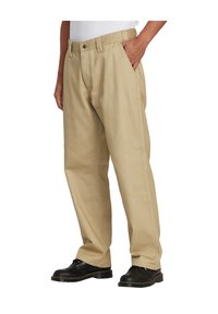 Pantalones de algodón color beige con un corte relajado, que cuentan con bolsillos laterales, cremallera y una textura suave. Combinados con zapatos negros.