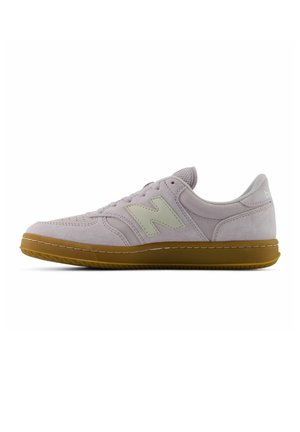 Hellvioletter Veloursledersneaker mit beigem "N" Logo, brauner Gummisohle und Schnürdesign, von der Seite auf weißem Hintergrund gezeigt.