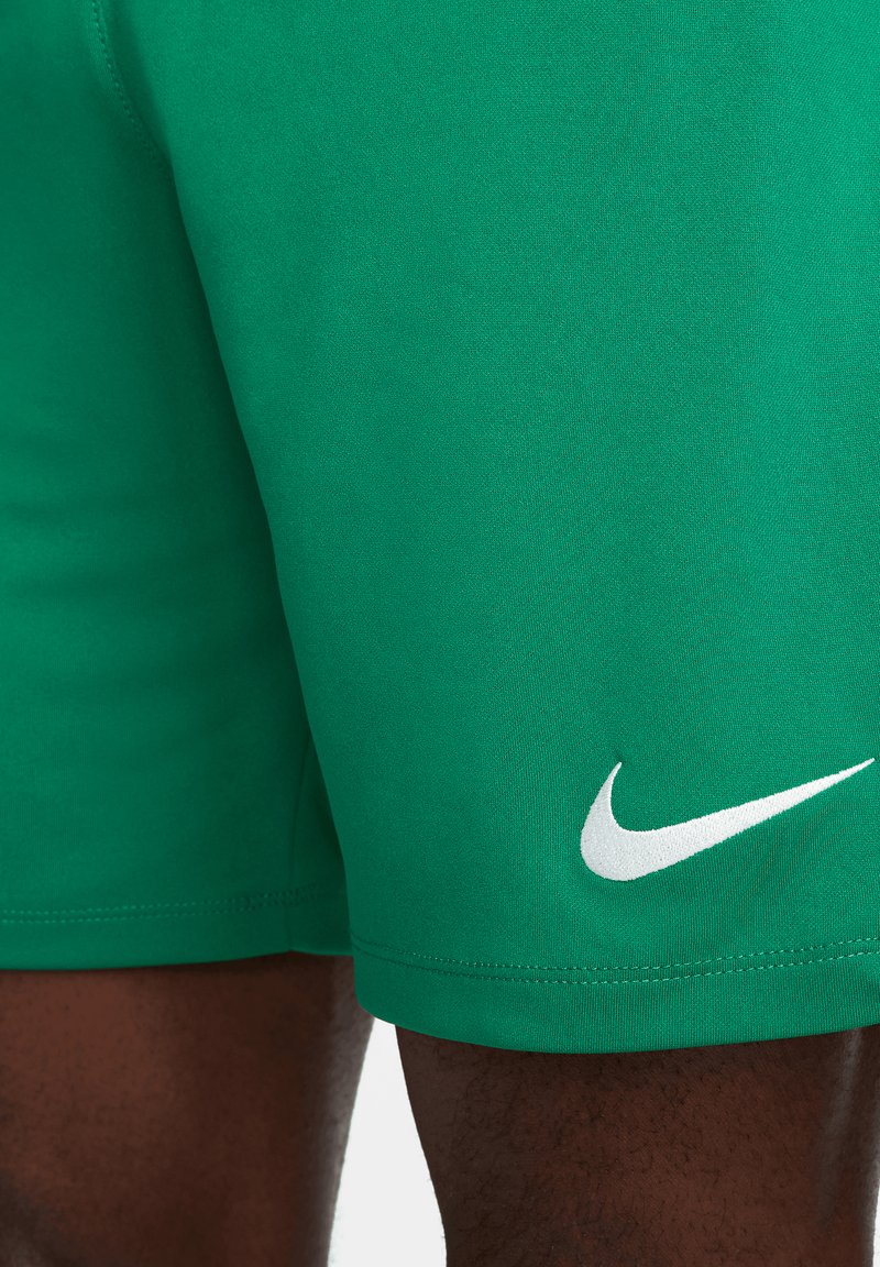 Pantalones cortos deportivos verdes hechos de un tejido suave, con un logo blanco de Nike en la parte inferior de la pierna. Detalles en las costuras y un diseño ajustado.