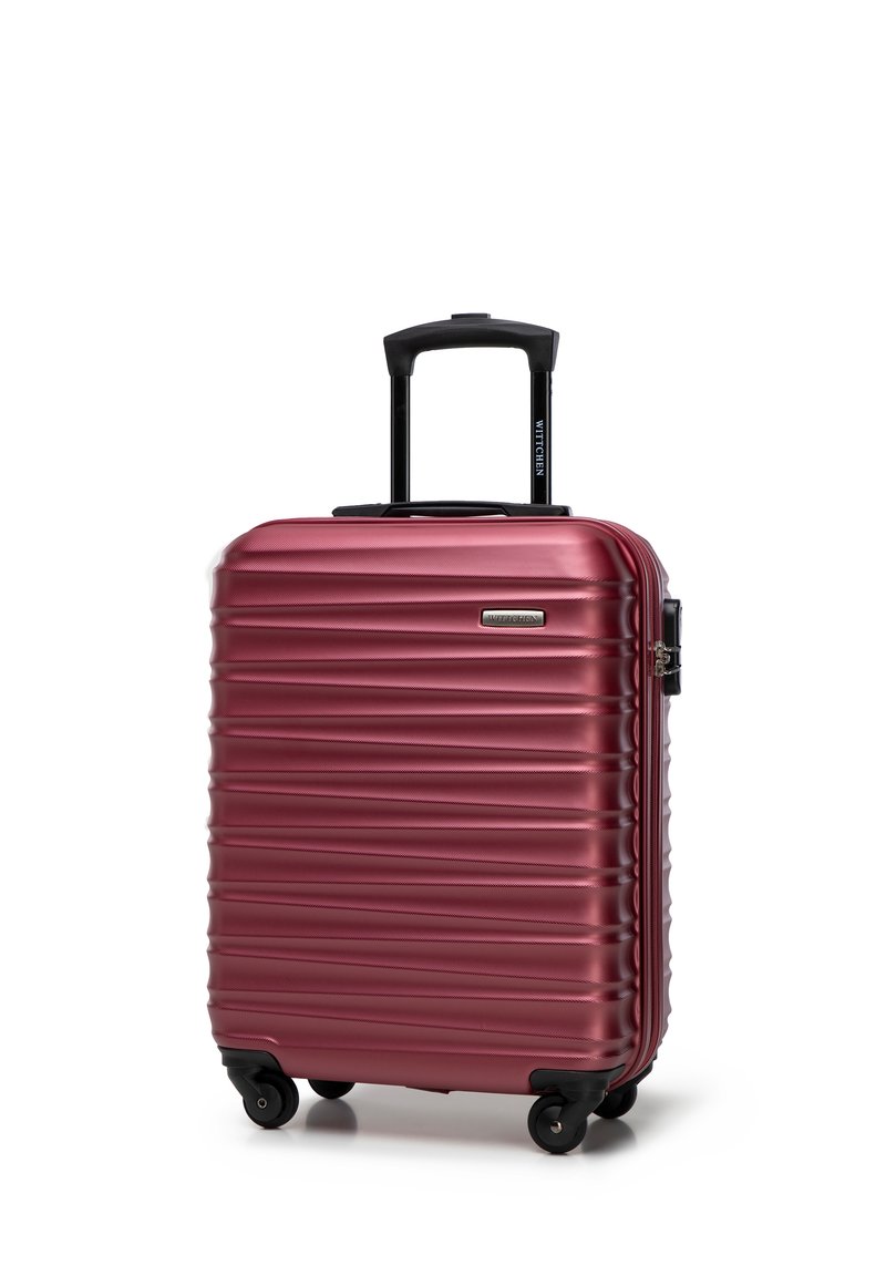 Valise rigide bordeaux avec texture striée horizontale, poignée rétractable noire et quatre roues pour la mobilité.
