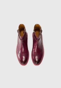 Bordo odinės aulinės botai su perforuotu dekoru, banginiu dizainu ir kontrastingu rožiniu padu. Šoninė užtrauktuko sistema lengvam užsidėtimui.
