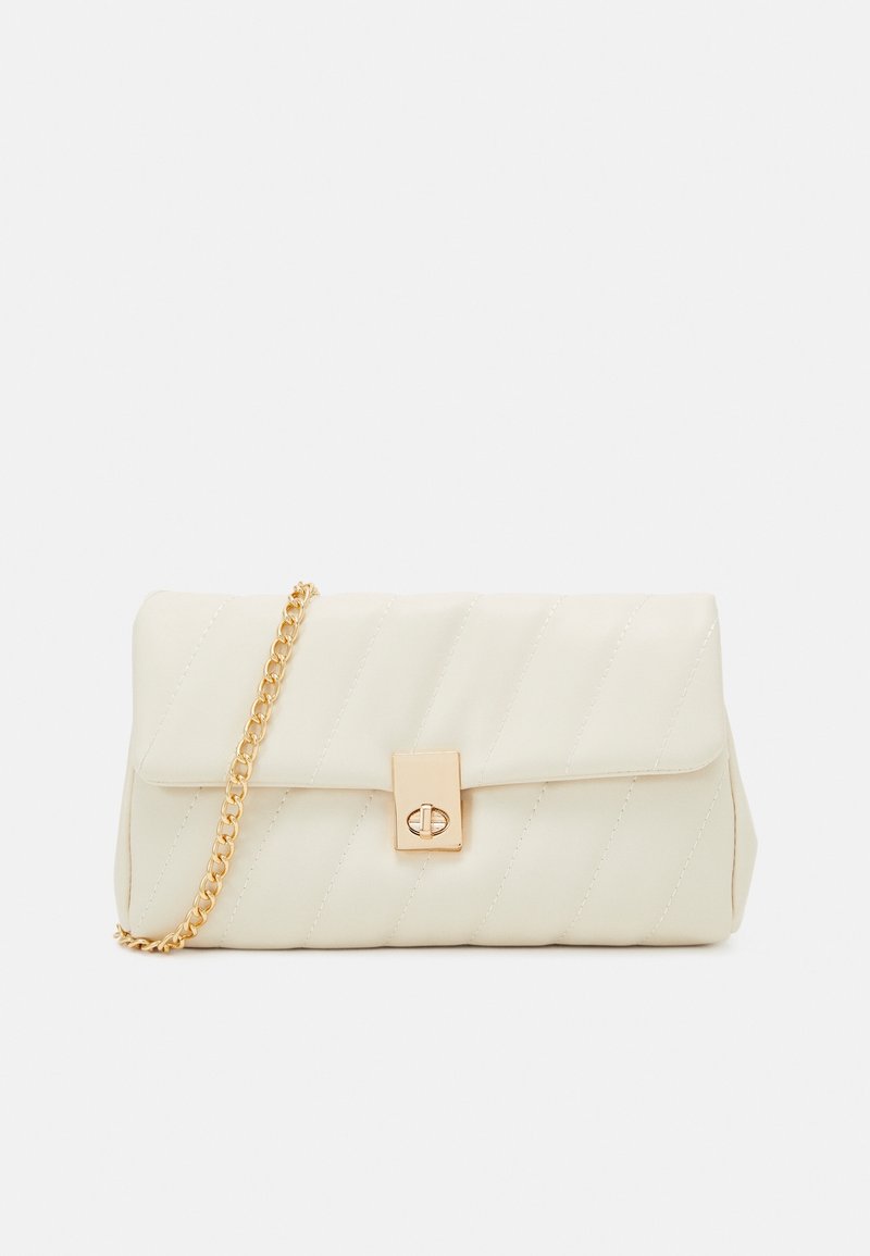 Pochette matelassée crème avec fermoir à tour doré et bandoulière chaîne dorée sur fond blanc.