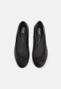 Ballerine in pelle nera con punta rotonda e un fiocco decorativo sulla parte anteriore. Texture liscia con soletta imbottita.