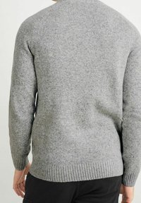 Pull gris en tricot avec une finition texturée, doté d'un col rond et de poignets et ourlet côtelés. La vue de dos montre une coupe décontractée.