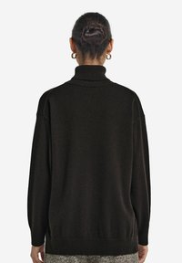 Czarny, oversize sweter z golfem, z prążkowanymi ściągaczami i dołem. Miękka tekstura, długie rękawy i opadające ramiona.