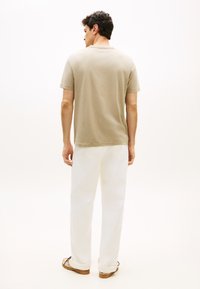 Μπεζ βαμβακερό t-shirt με λαιμόκοψη crew, συνδυασμένο με λευκό παντελόνι. Το σύνολο έχει άνετη γραμμή και διακριτική υφή.