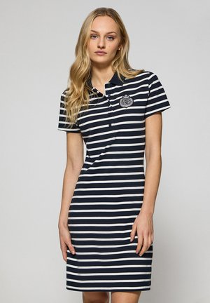 Abito polo a righe navy e bianche con maniche corte, colletto, bottoni frontali e un emblema decorativo sul lato sinistro del petto. Tessuto misto cotone.