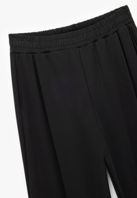 Czarne, lekkie spodnie z elastycznej tkaniny z szerokim elastycznym pasem, dwiema bocznymi kieszeniami i detalami w postaci plisowanego przodu.