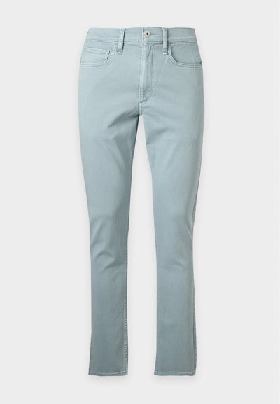 Jean slim fit bleu clair avec bouton à l'avant, fermeture éclair et design cinq poches sur fond blanc uni.