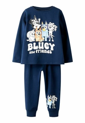 Set za pidžamu u tamnoplavoj boji od pamuka s dugim rukavima, grafikonom crtanih pasa i natpisom "Bluey i prijatelji". Usuglašene hlače s bočnim printom.