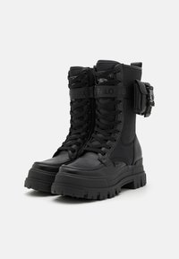 Bottes de combat noires en cuir et textile, semelle crantée, lacets à l'avant et détail de sangle ajustable.