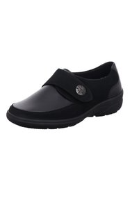 Black shoe featuring a combination of leather and suede, rounded toe, velcro strap closure, and a silver circular accent.