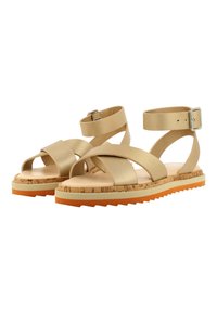 Sandalias planas beige con múltiples tiras cruzadas y una correa para el tobillo. Plantilla de corcho y suela de goma naranja con borde serrado. Detalle de hebilla plateada.