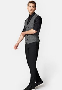 Szary kamizelka w kratę z podwójnym zapięciem, noszona na czarnej koszuli. W połączeniu z czarnymi spodniami wizytowymi i trampkami. Gładka tekstura.
