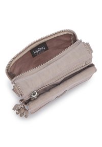 Beige Kipling pung lavet af stof med en struktureret overflade. Indeholder en lynlås lukning, to rum og en dekorativ abe-nøglering.