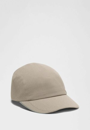 Gorra beige hecha de tela texturizada con visera curvada y superficie suave, que presenta un diseño minimalista sin marcas ni adornos visibles.
